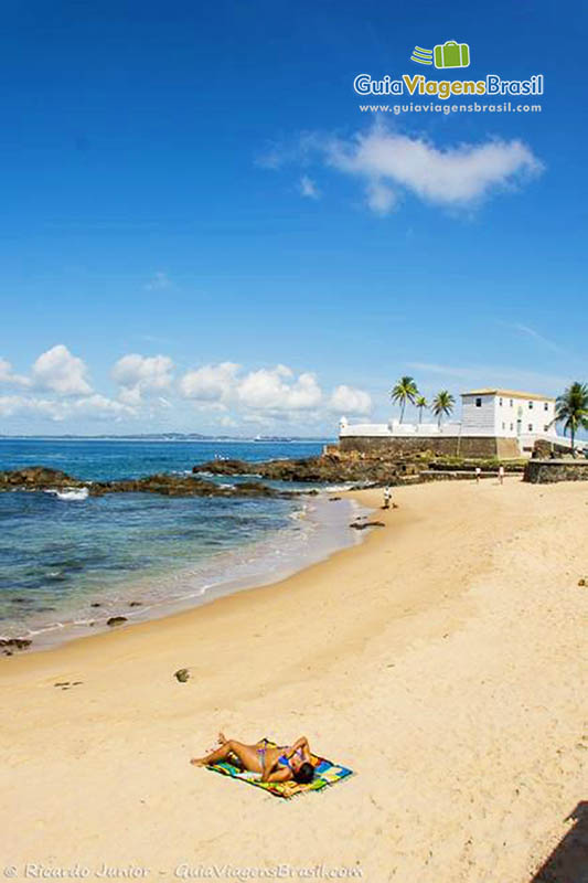 Imagem de turista aproveitando o sol da Praia Porto da Barra.