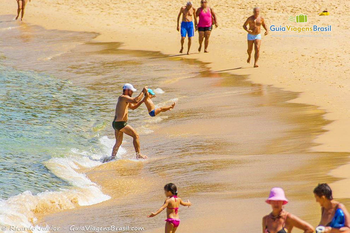 Imagem de pai e filho brincando na beira da água, na Praia de Porto da Barra.
