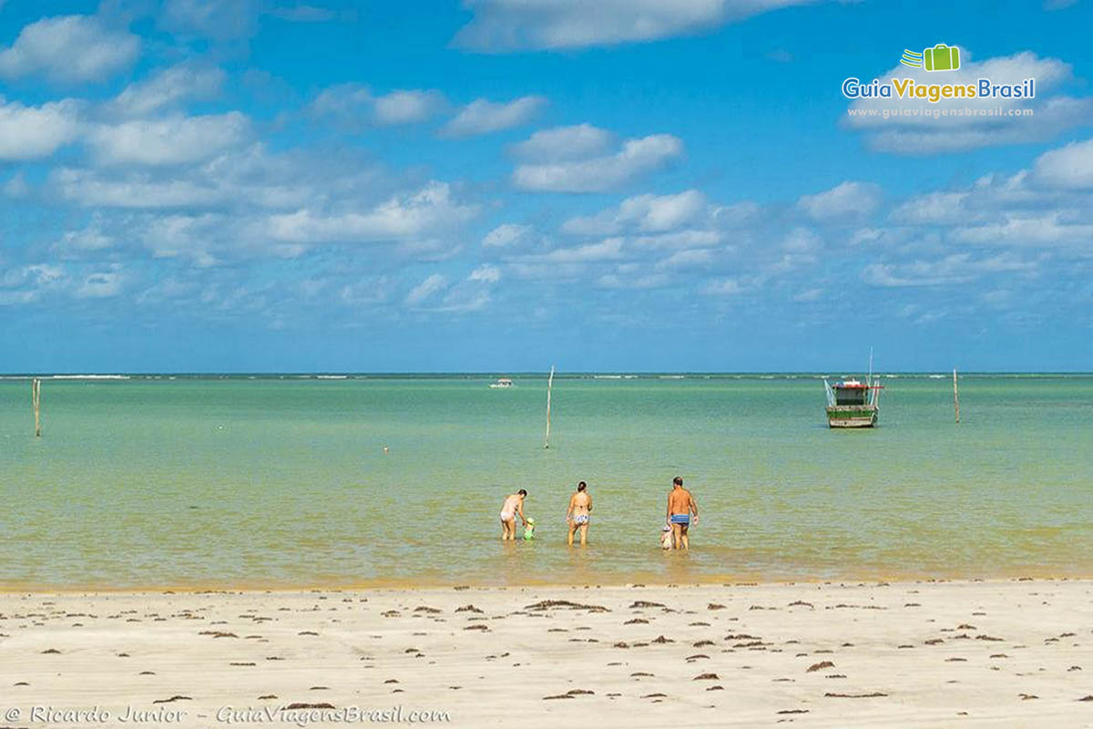 Imagem de família aproveitando uma bela tarde de sol na praia.