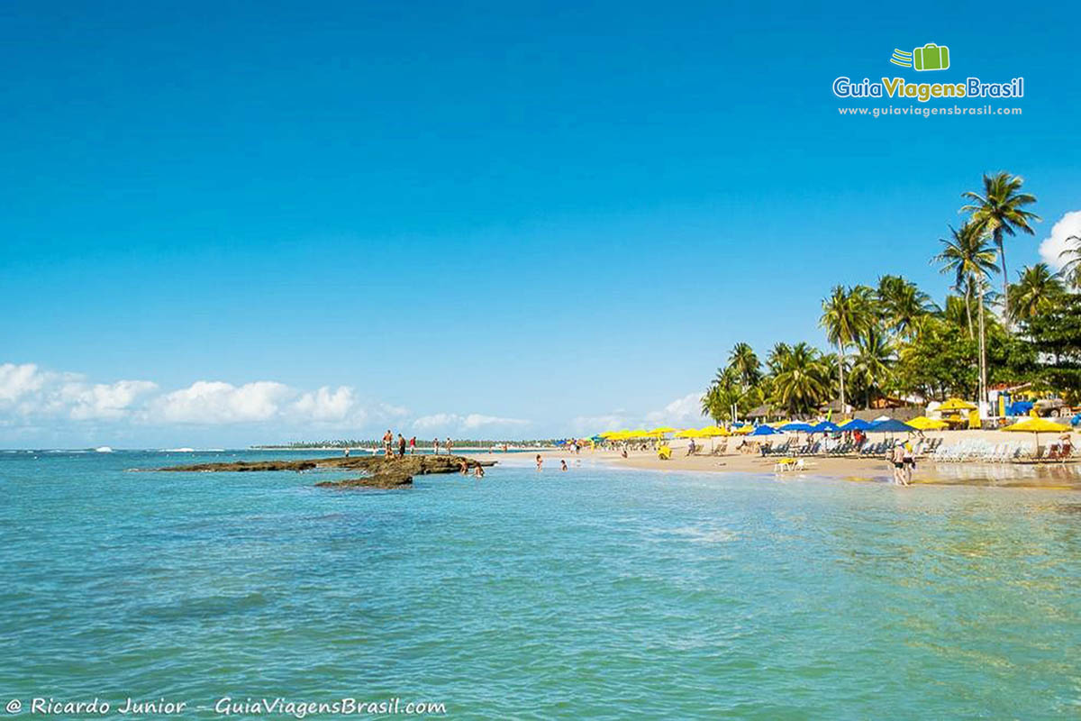 Imagem de turistas nas pedras na praia em Pernambuco.