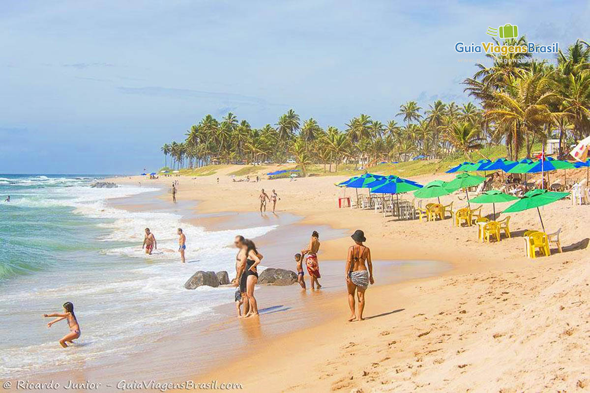 Imagem de turistas na beira da Praia da Stella Maris, em Salvador.