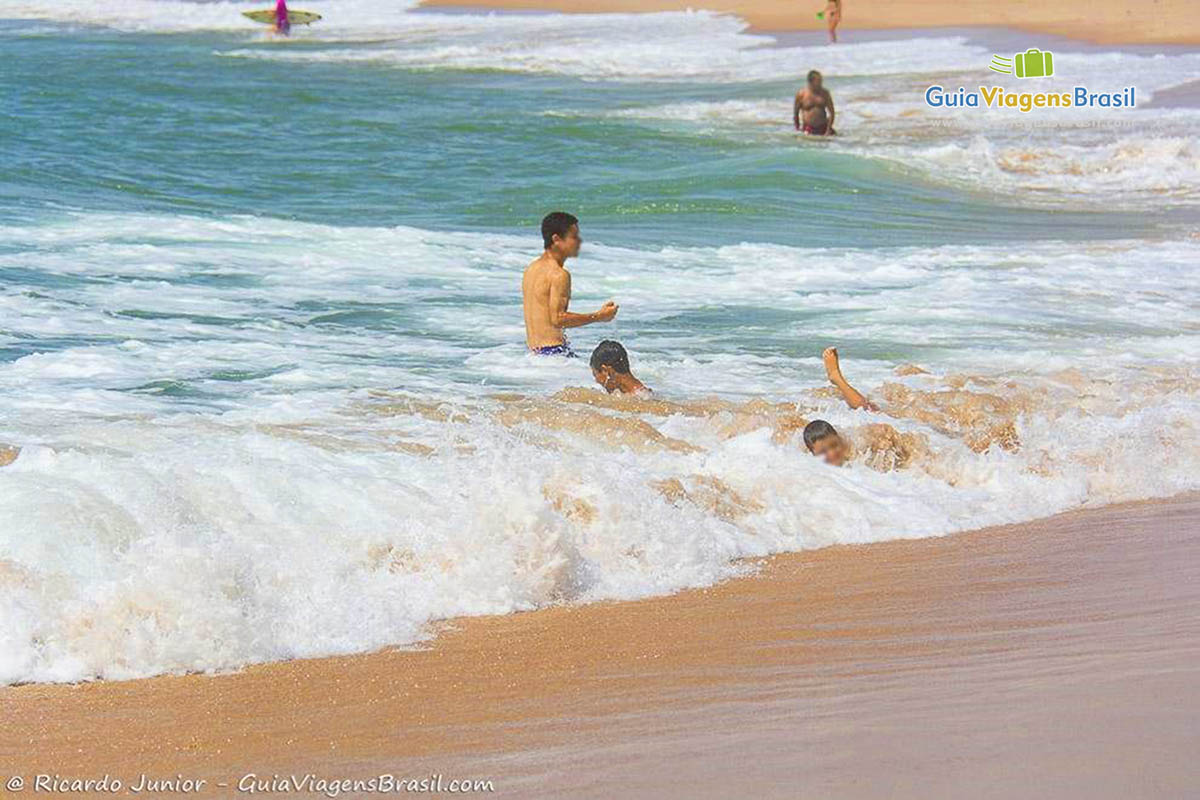 Imagem de crianças brincando nas ondas na Praia Stella Maris.