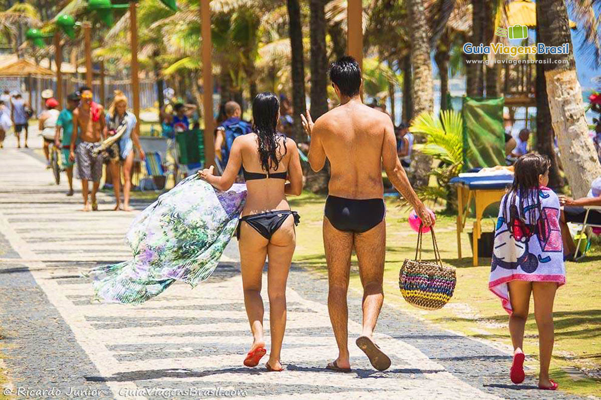 Imagem de família caminhando na orla da praia.