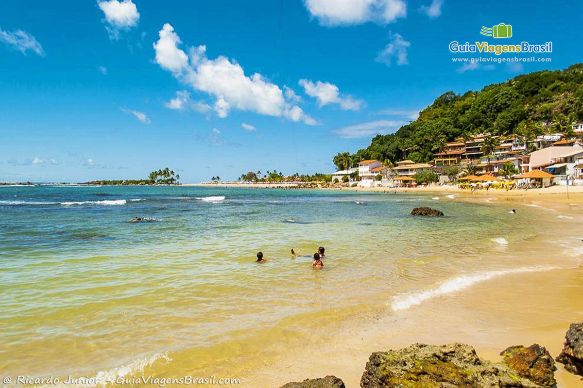 Imagem de crianças brincando nas águas cristalinas da primeira praia.