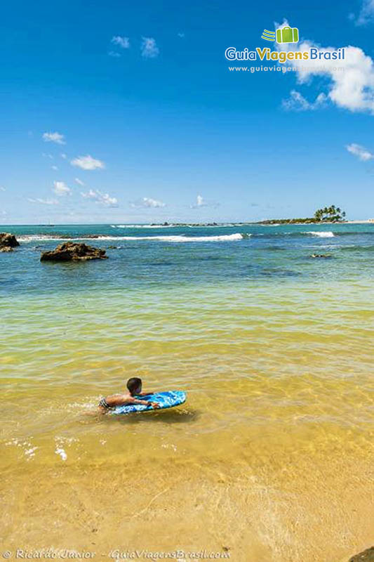 Imagem de criança brincando na prancha na primeira praia.