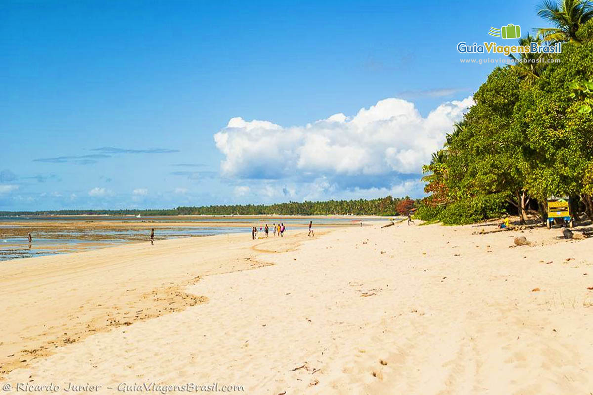 Imagem de turistas caminhando nas areias da Quarta Praia.