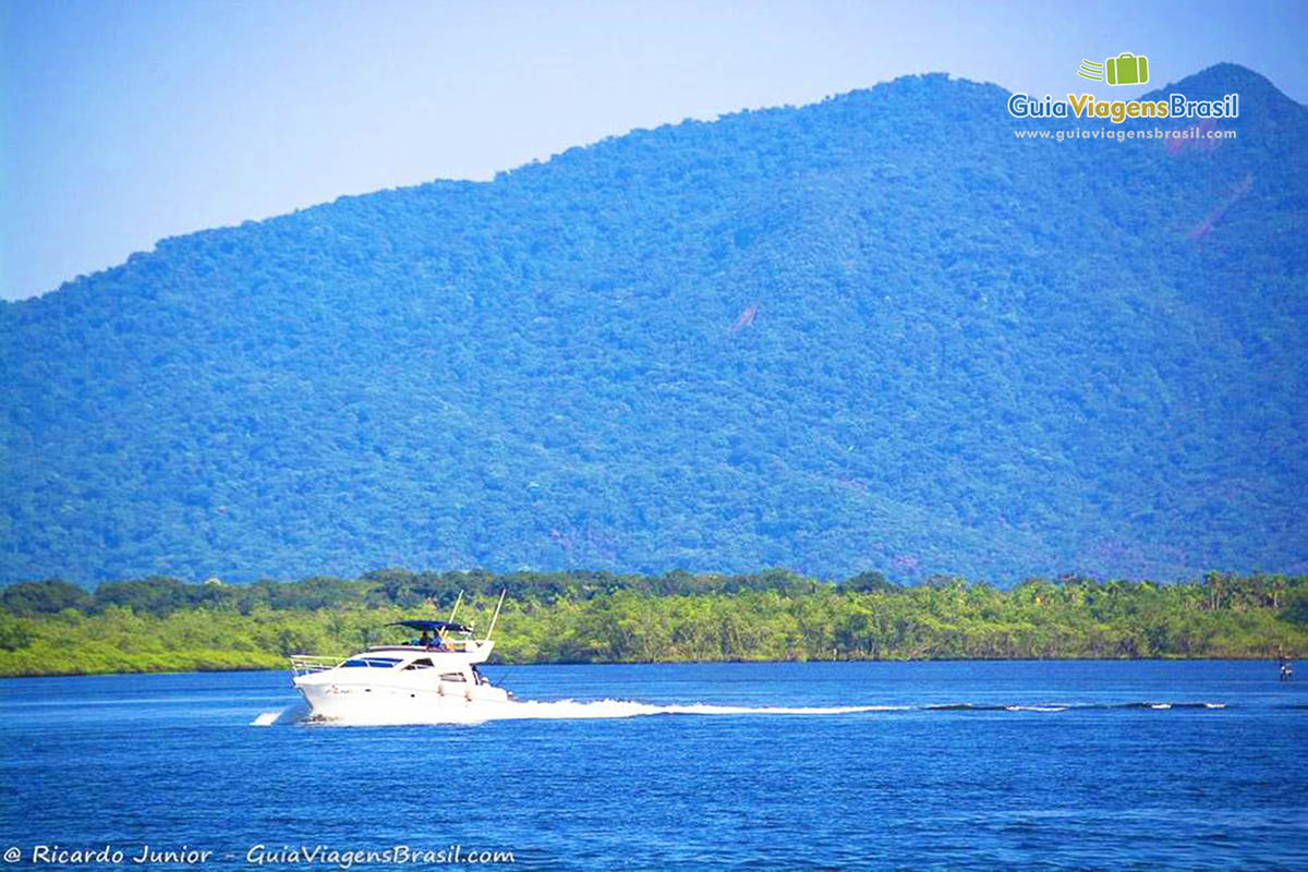 Imagem de barco passando ao lado da balsa em Guaratuba, Santa Catarina, Brasil.