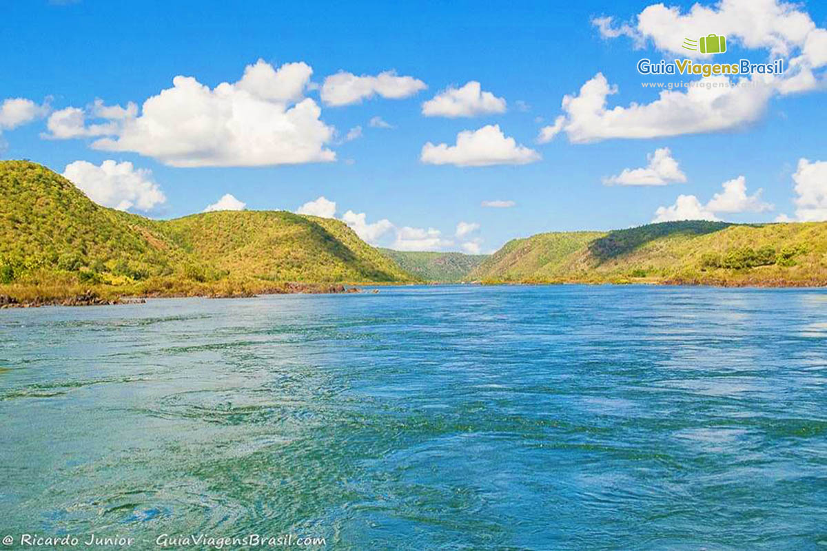 Imagem do rio de águas azuis e morros nas margens.