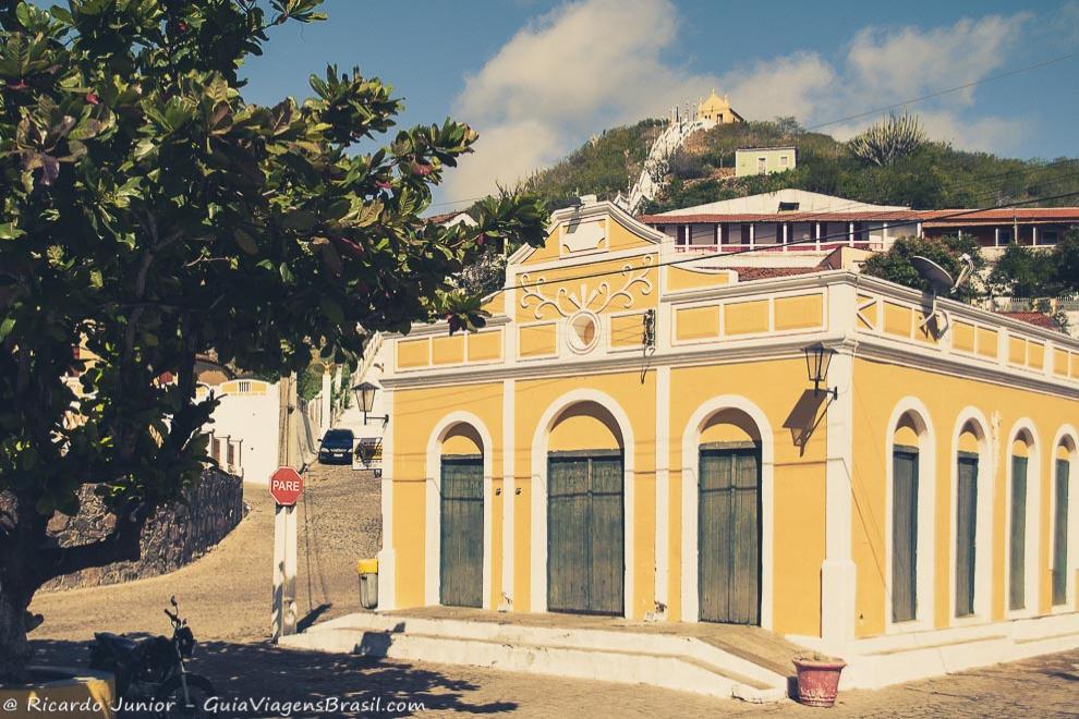 Imagem de belo casarão amarelo na praça.