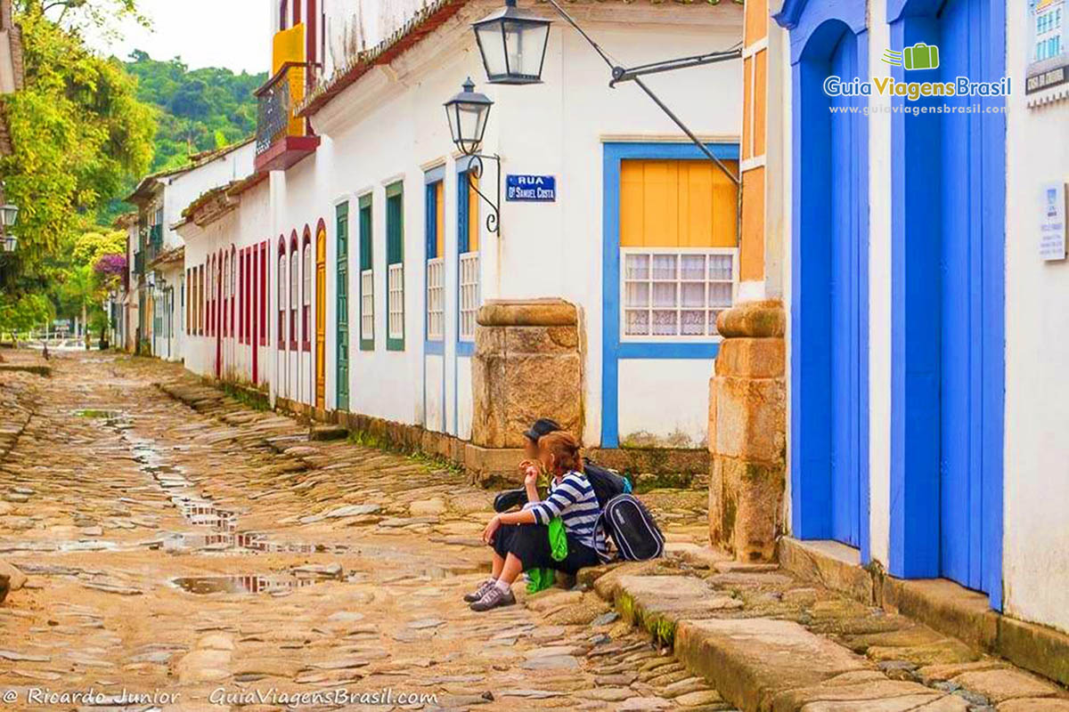 Imagem de dois amigos turistas sentados na calçada.