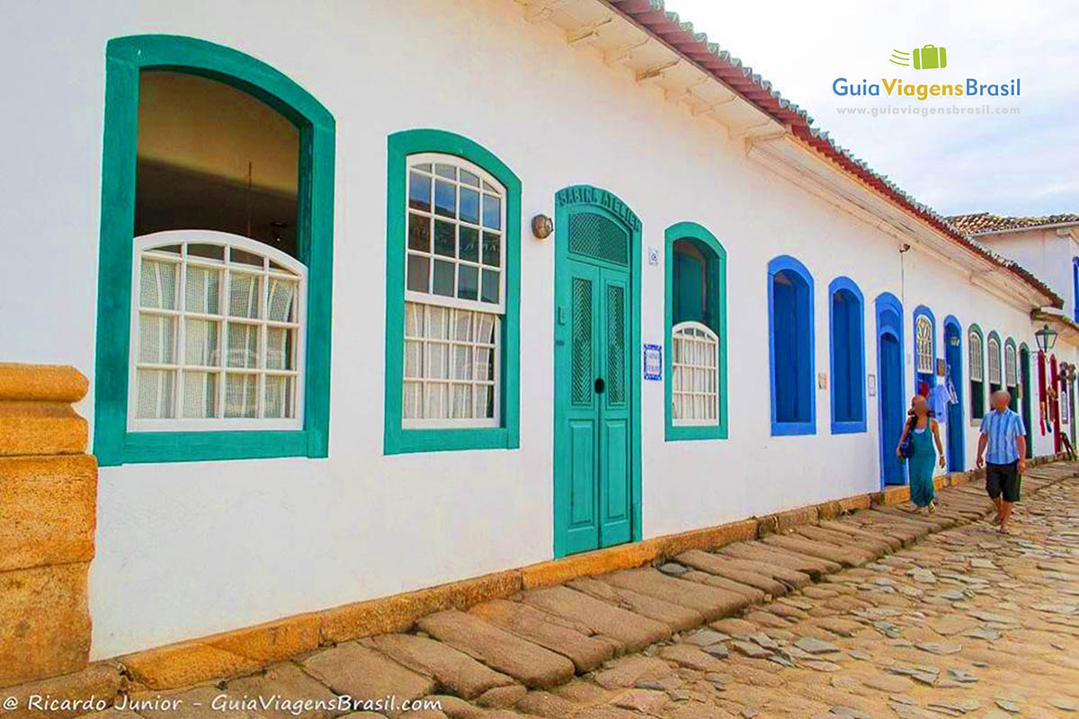 Imagem de fachadas de casas com turistas caminhando pela calçada no centro da cidade.