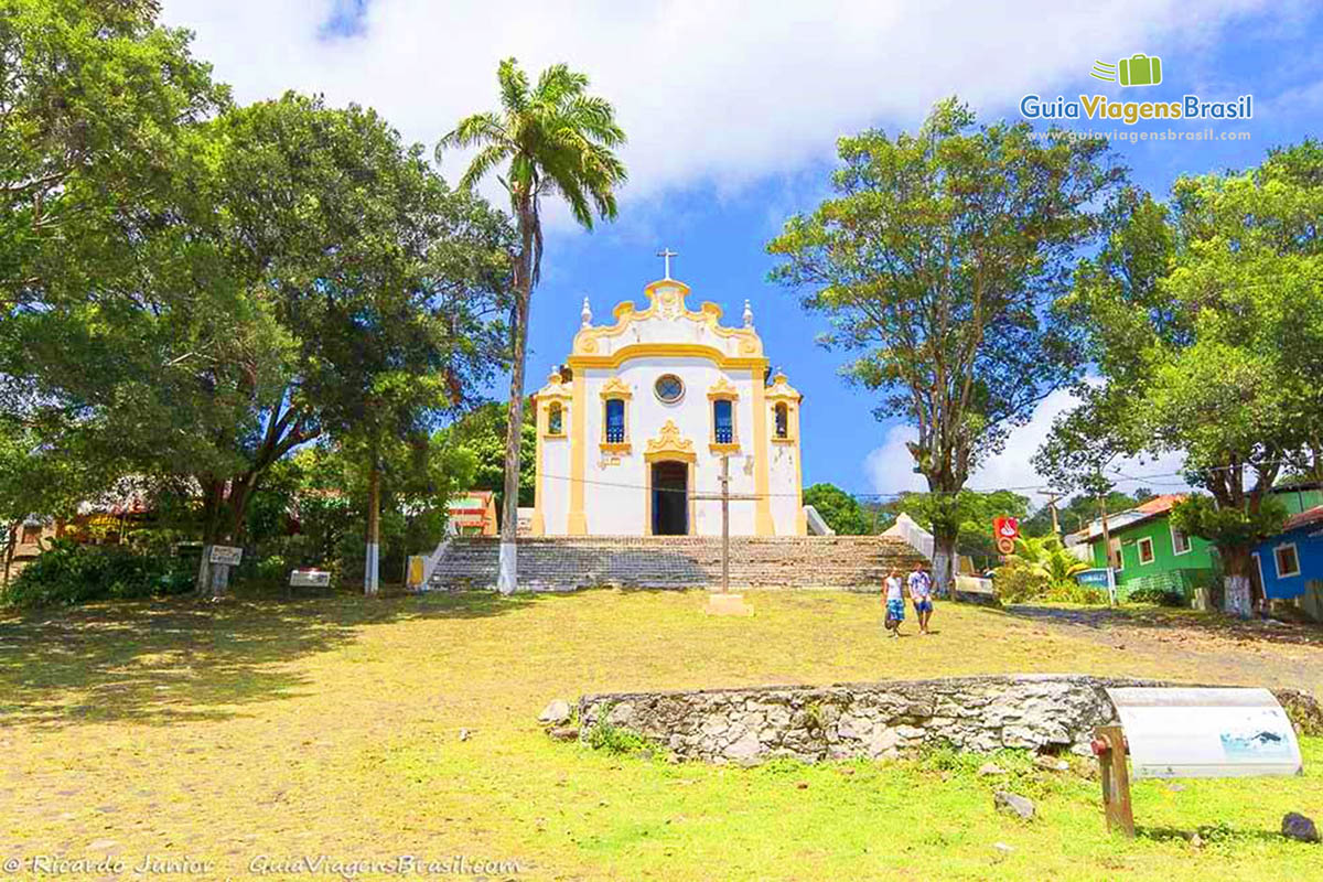 Imagem do gramado, crucifixo e ao fundo a Igreja de Nossa Senhora dos Remédios, em Fernando de Noronha, Pernambuco, Brasil.