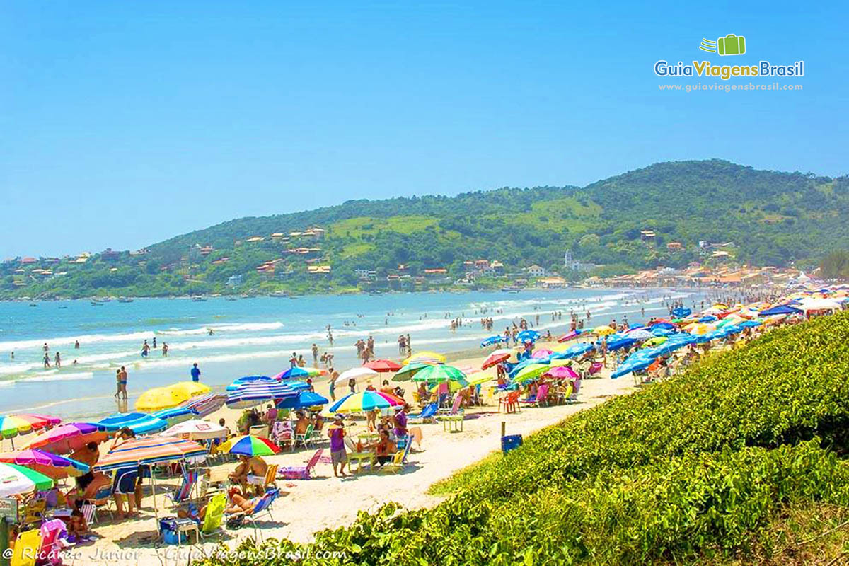 Imagem da praia repleta de turistas.