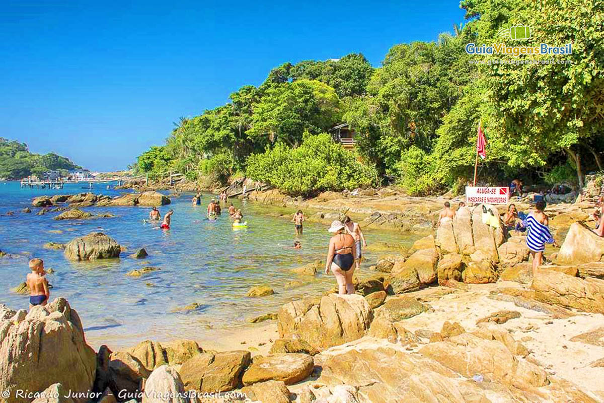 Imagem de pessoas nas pedras da praia.