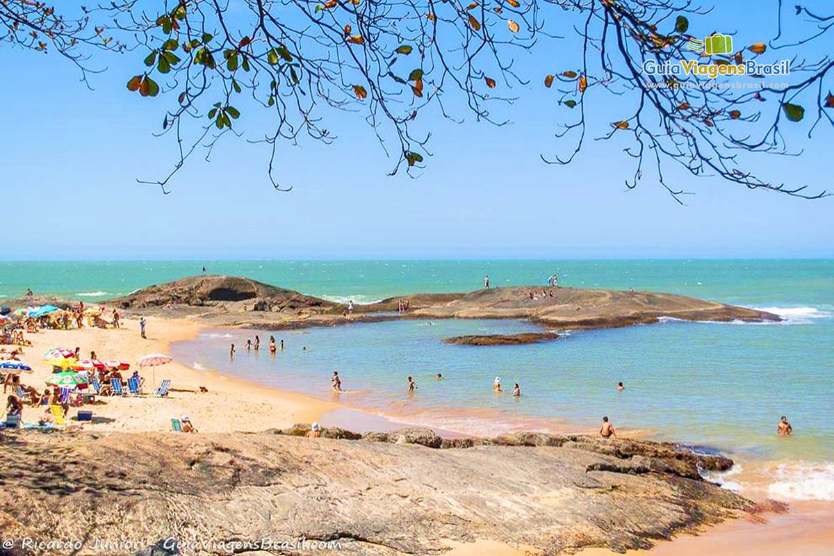 Imagem de pessoas nas pedras curtindo o belo dia em Guarapari.