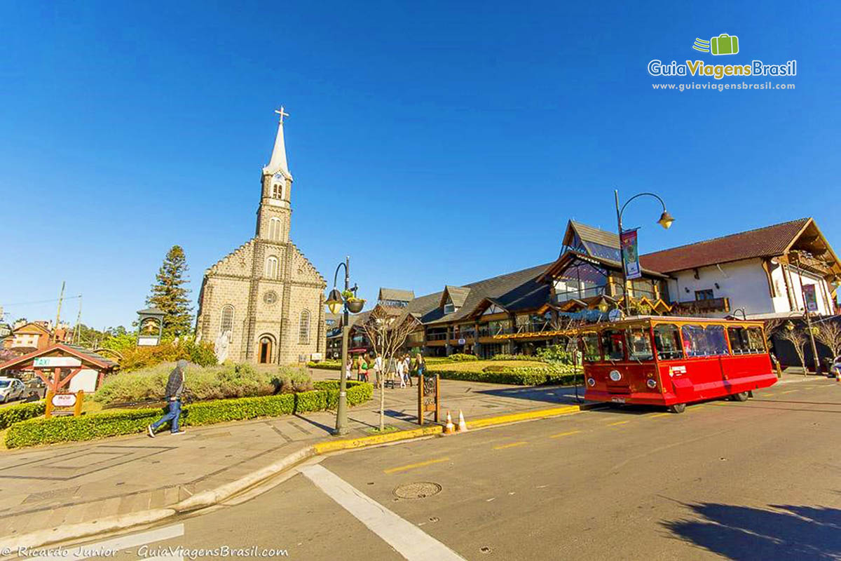 Imagem de um ônibus vermelho parado na frente da Igreja de São Pedro.