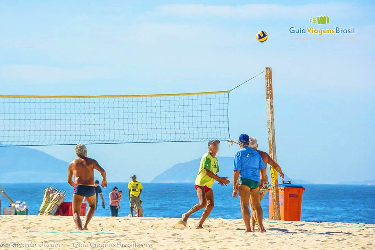 Imagem de amigos jogando futevôlei nas areias da praia.