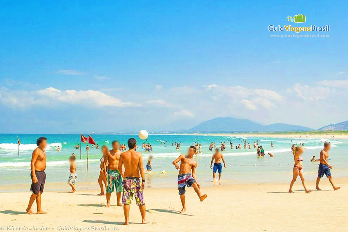 Imagem de amigos jogando vôlei na Praia Joaquina.