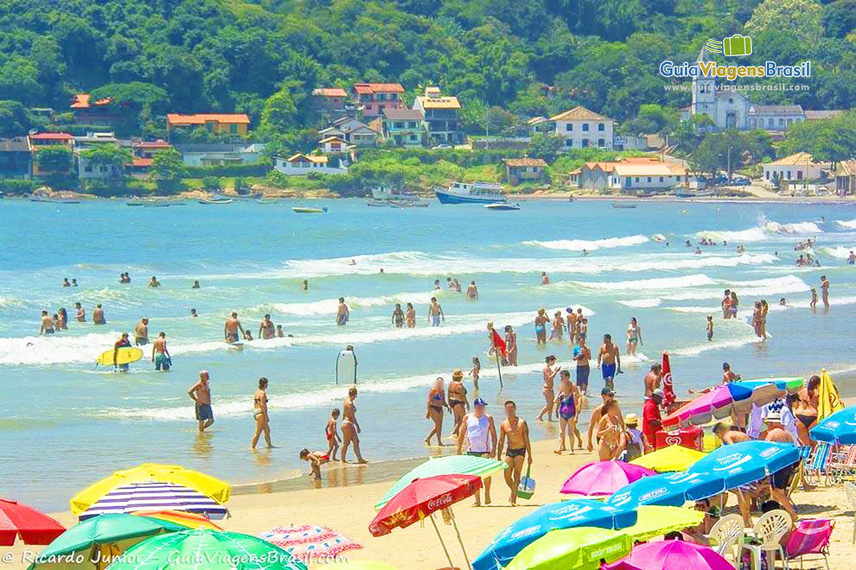 Imagem de pessoas dentro do mar aproveitando um belo dia de sol.