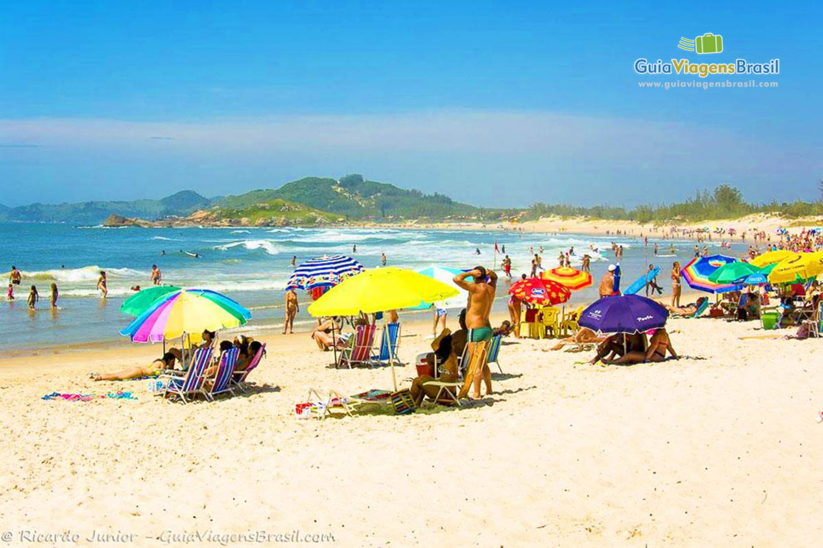 Imagem de guarda sol coloridos nas areias da praia.