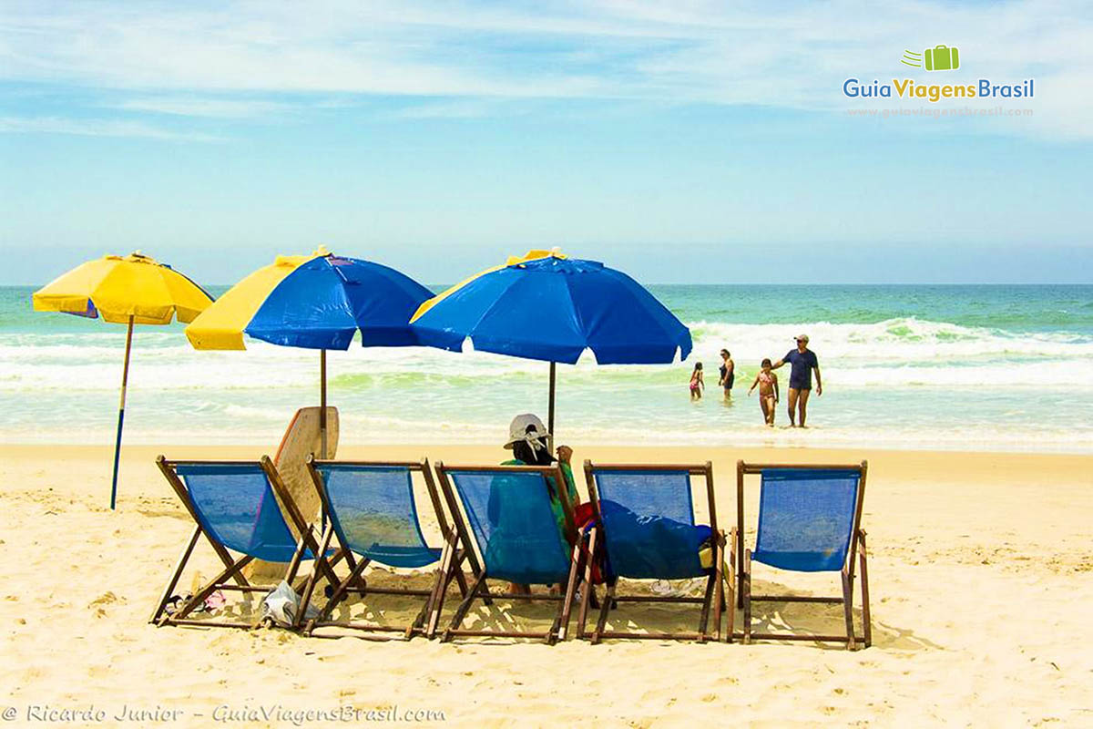 Imagem de cadeiras e guarda sol azul na Praia do Santinho.