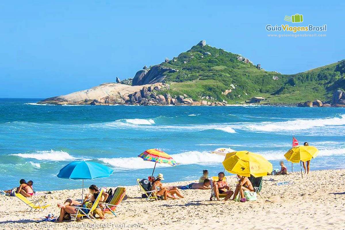 Imagem de várias pessoa com seus guarda sol na Praia Mole.