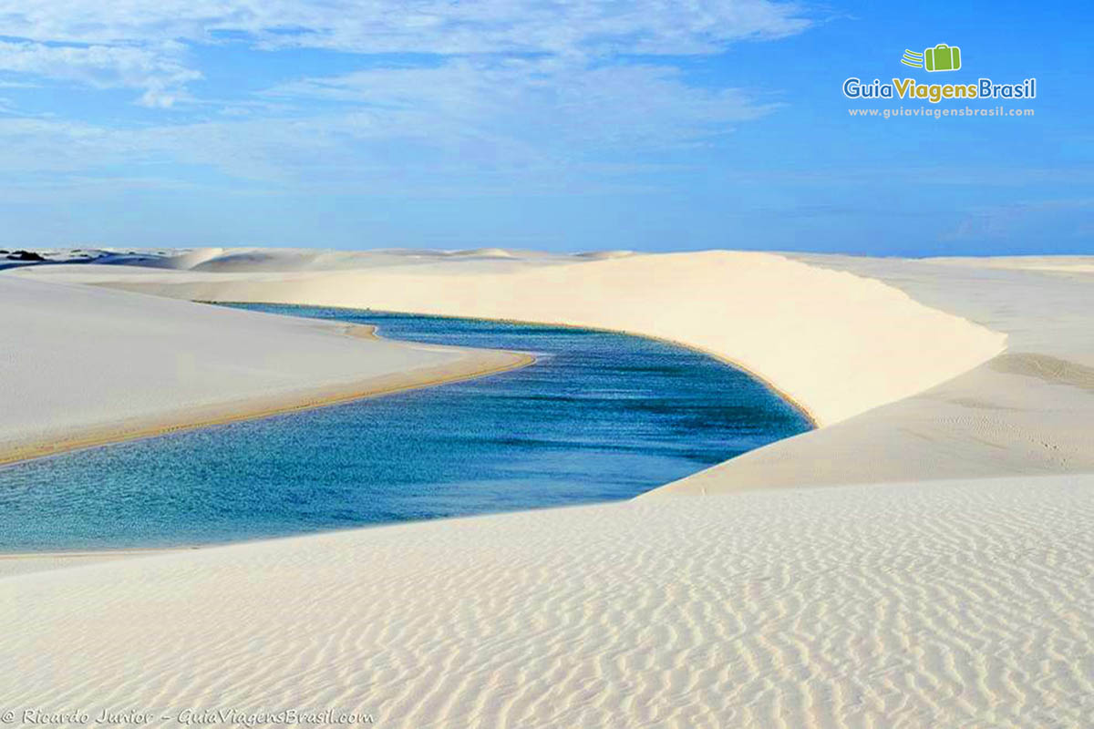 Imagem de um caminho de águas no meio das dunas brancas.