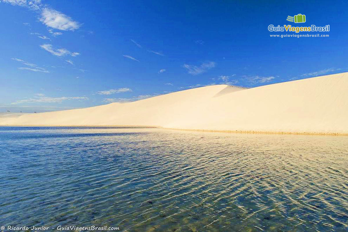 Imagem das águas transparentes e ao fundo as lindas dunas.
