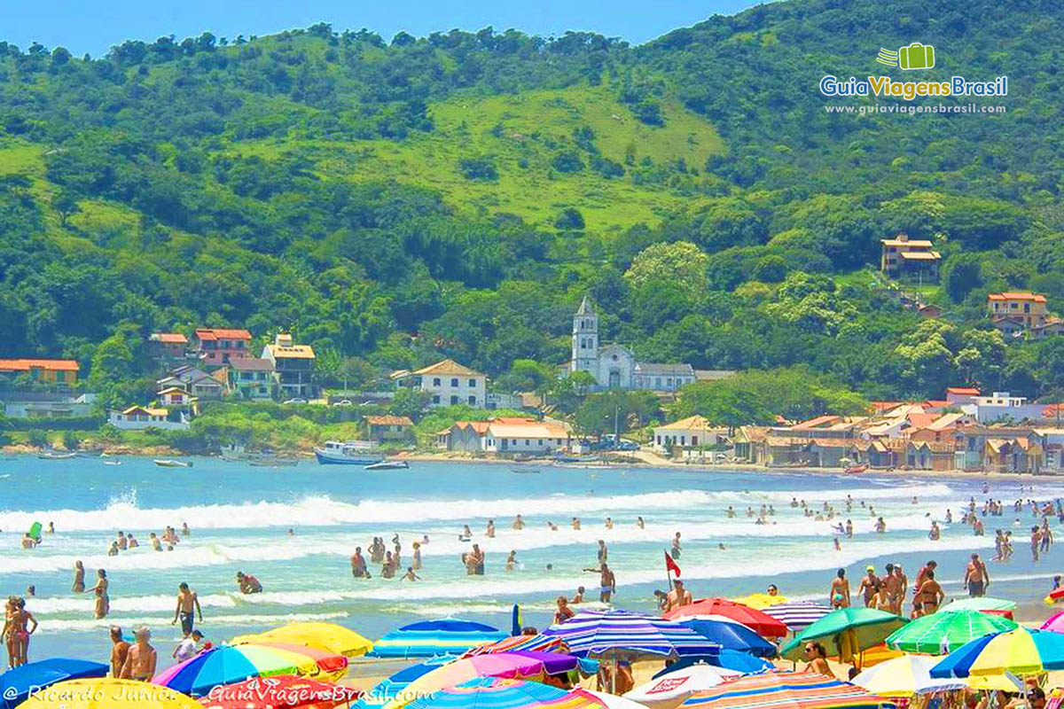 Imagem do belo mar a ao fundo a vegetação verdinha do morro.