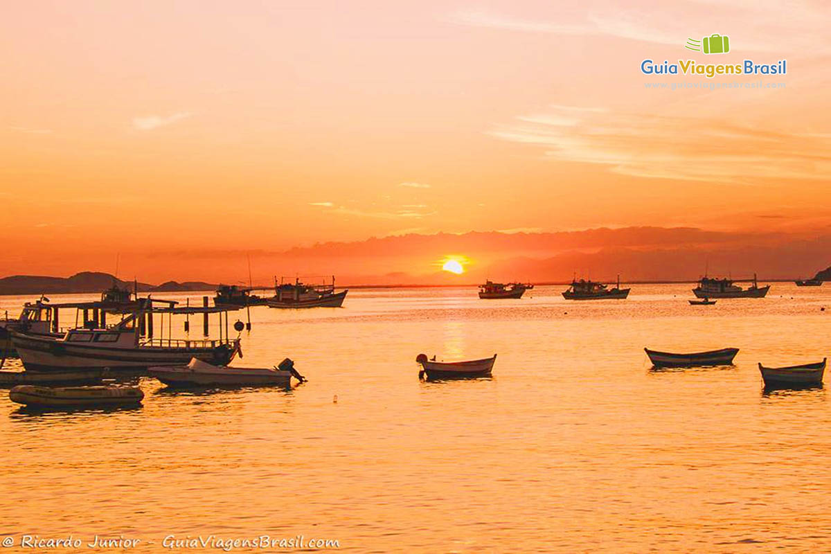 Imagem da bela Praia da Armação repleta de barcos no mar em um encantador entardecer.