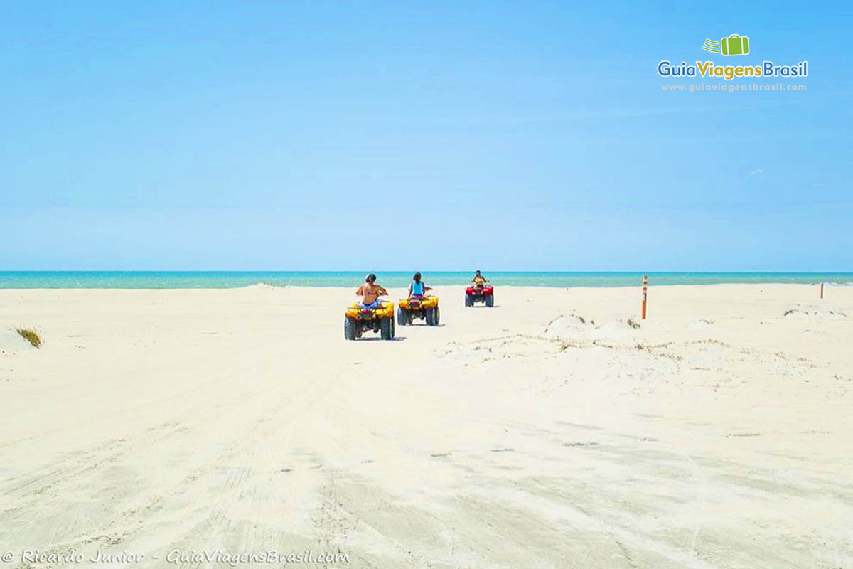 Imagem de três bugues na areia da praia.