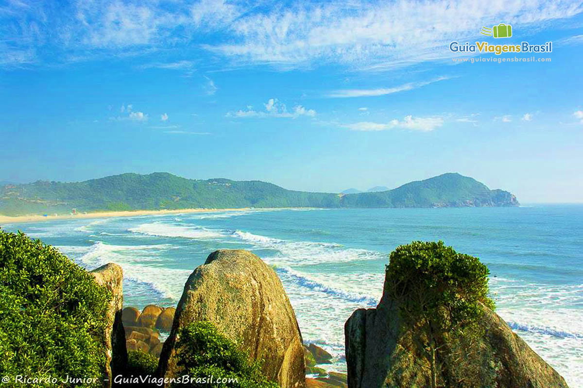 Imagem das pedras e ao fundo o mar da Praia do Rosa.