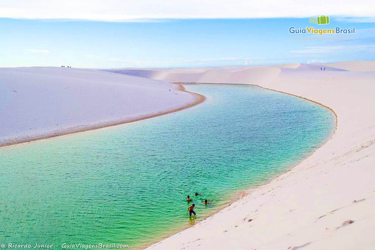 Imagem de das águas em um tom azul esverdeado e turistas aproveitando para se banhar.