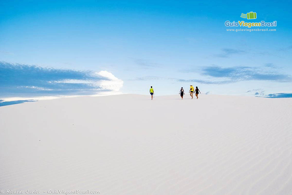 Imagem de turistas passeando pelas dunas e o azul maravilhoso do céu no Maranhão.