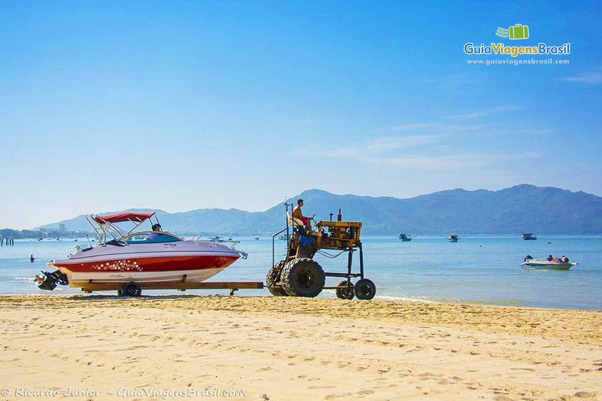 Imagem de um carro trazendo lancha para a beira do mar.