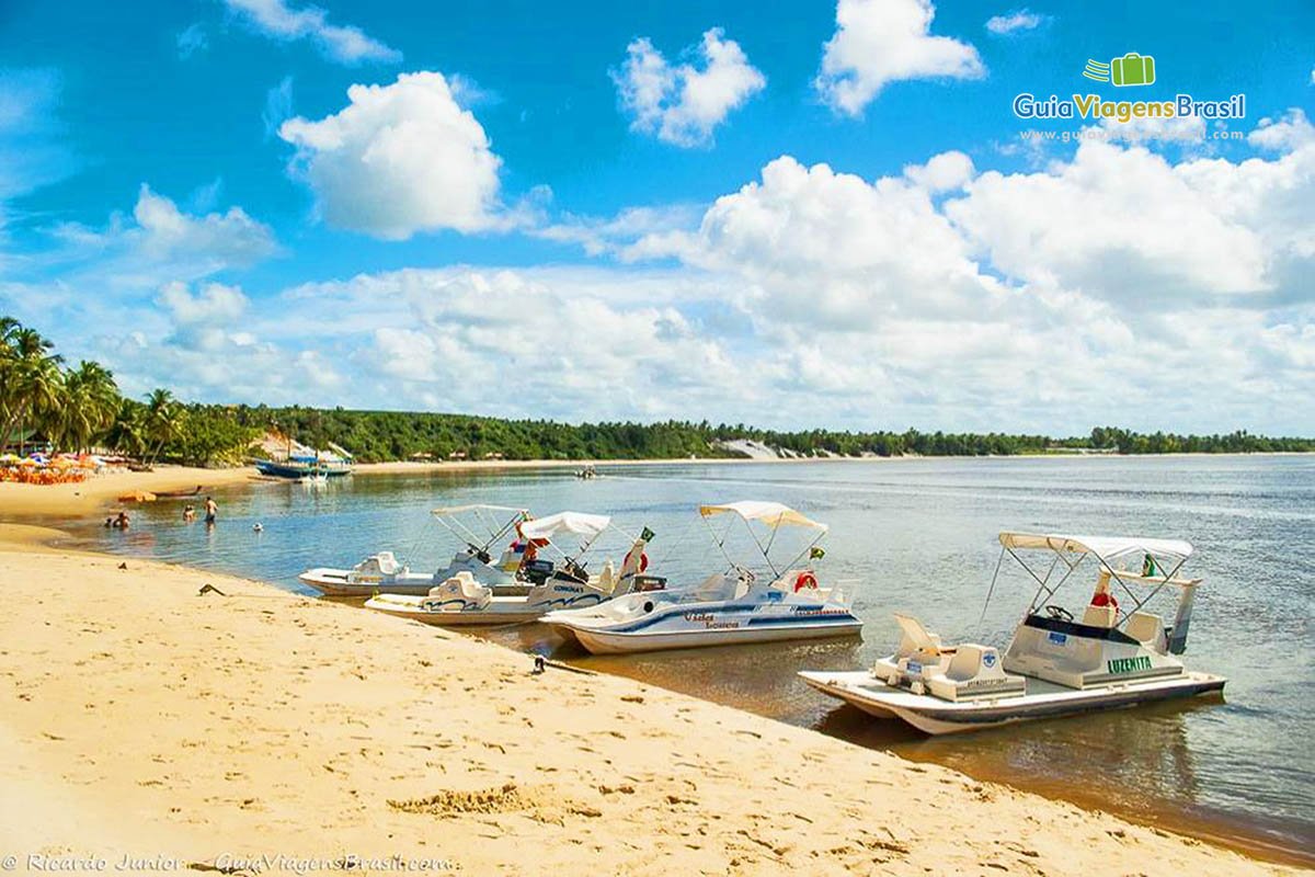 Imagem de pequenas lanchas para passeio parada na beira da Praia.