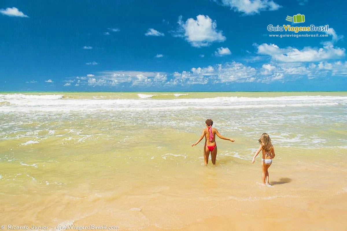 Imagem de mãe e filha entrando no mar da linda praia do Recife.