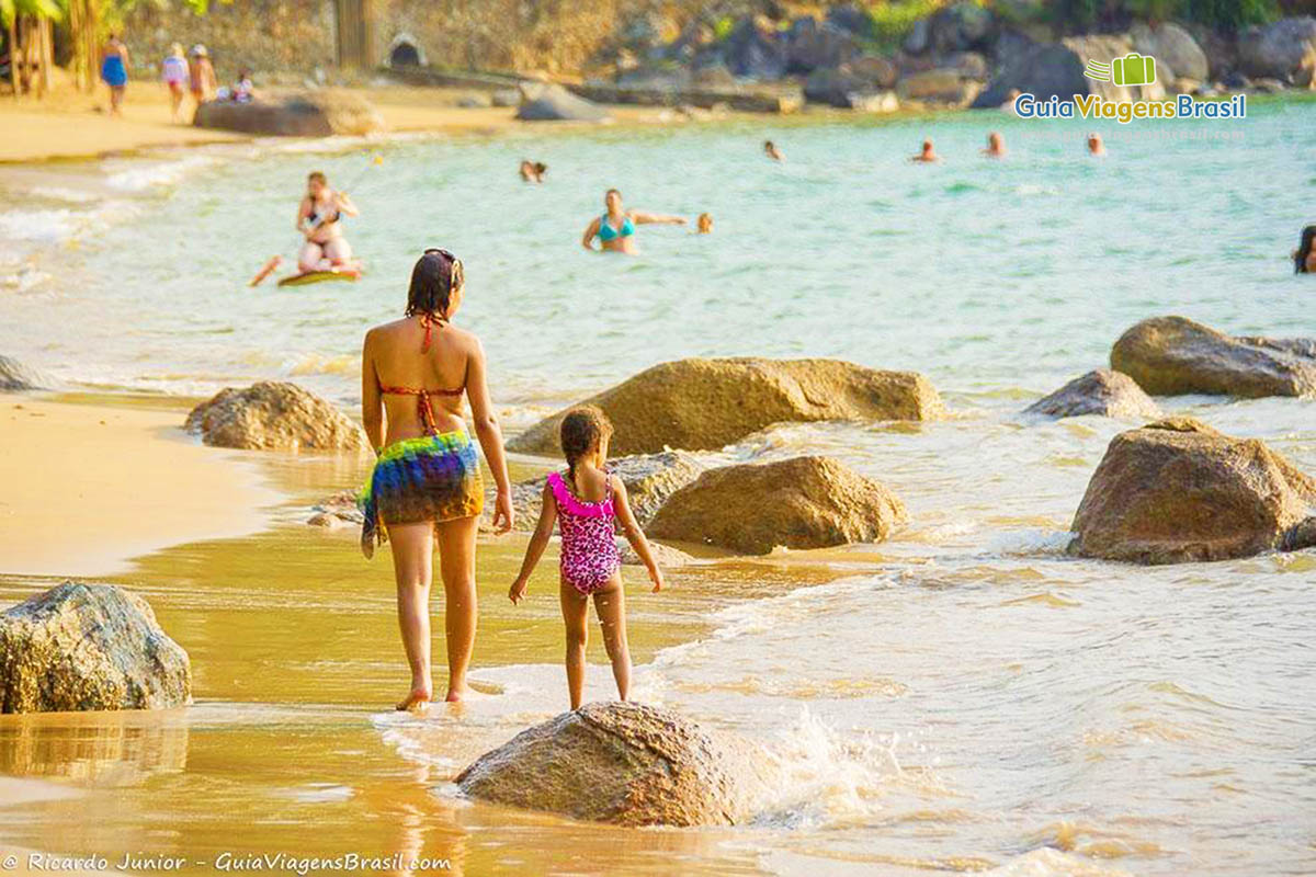 Imagem de mãe e filha na praia em Ilhabela.