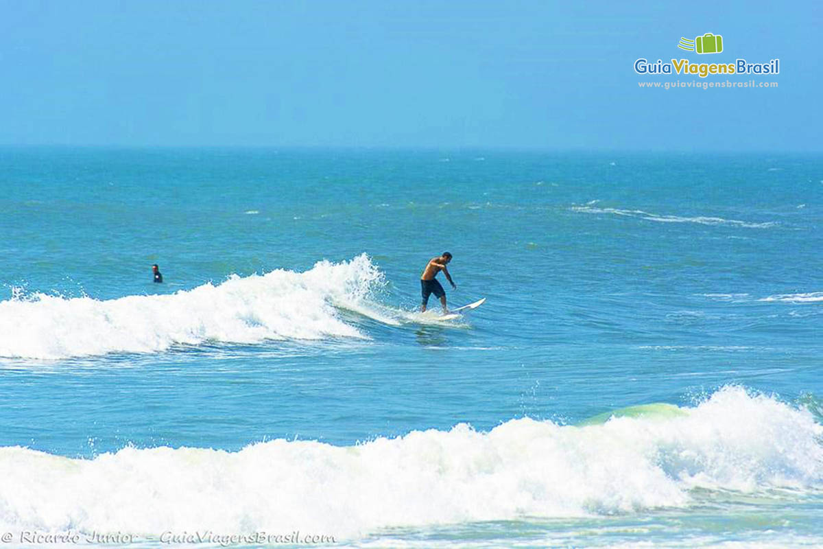 Imagem de surfista fazendo manobras no pico da onda.