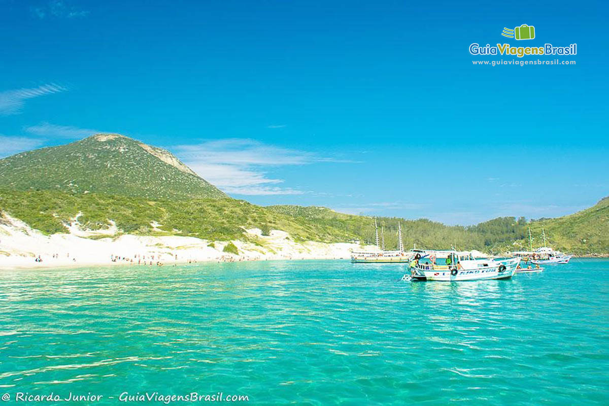 Imagem dos barcos mais afastados da ilha e os turistas se divertindo na ilha.