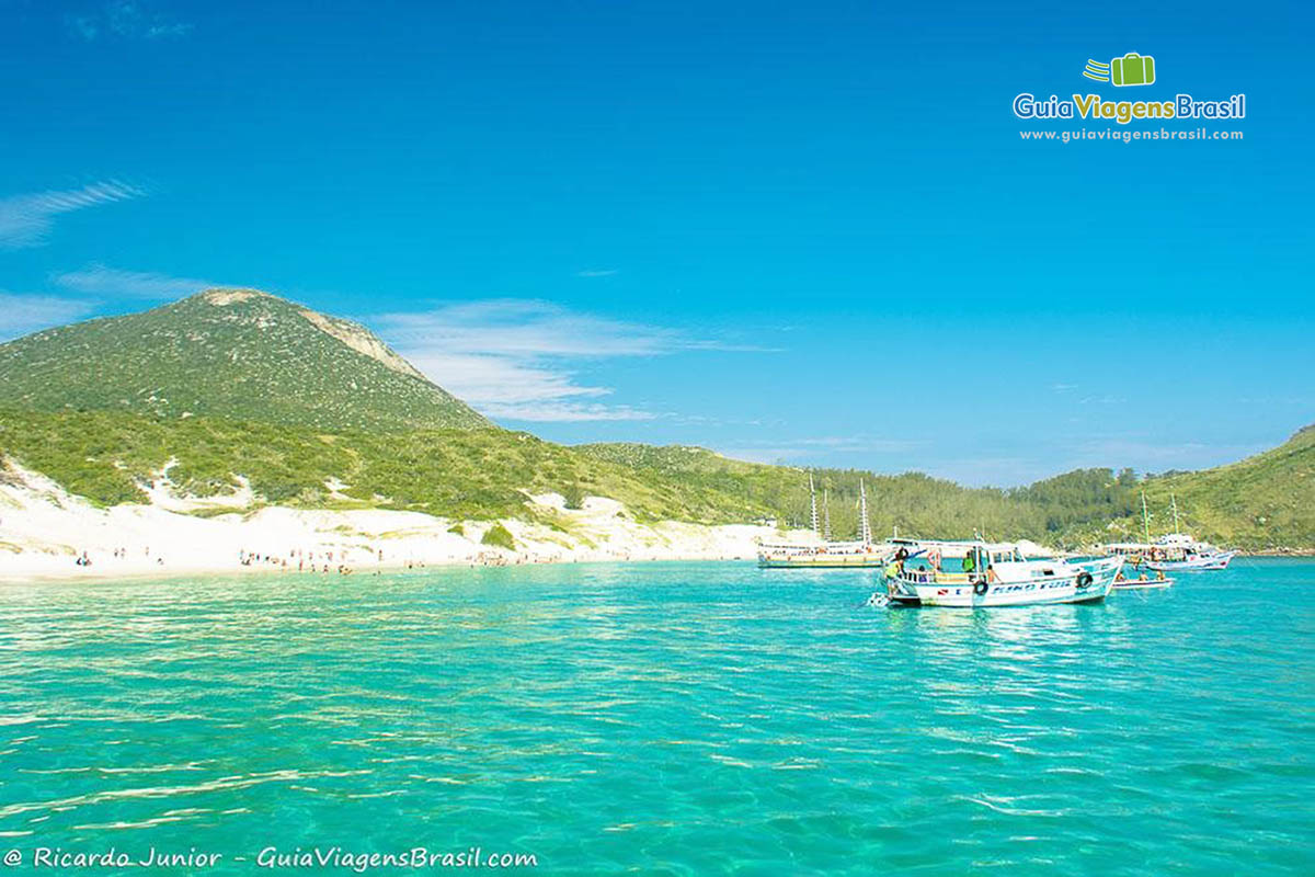 Imagem dos barcos mais afastados da ilha e os turistas se divertindo na ilha.