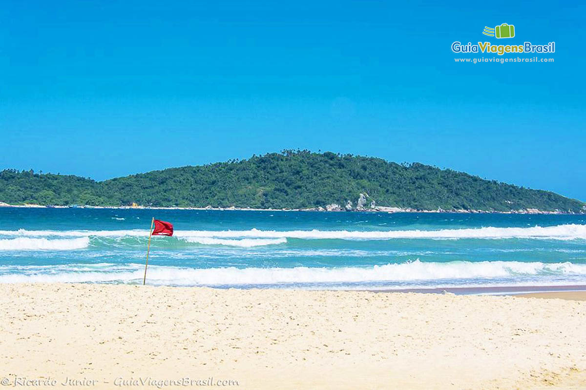 Imagem de bandeira vermelha na beira da Praia Campeche.