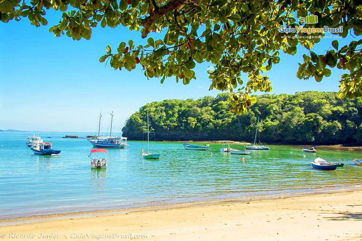 Imagem do mar calmo e poucos barcos na praia. Pois da Praia dos Ossos tem saída de passeios de barcos para orla de Búzios.