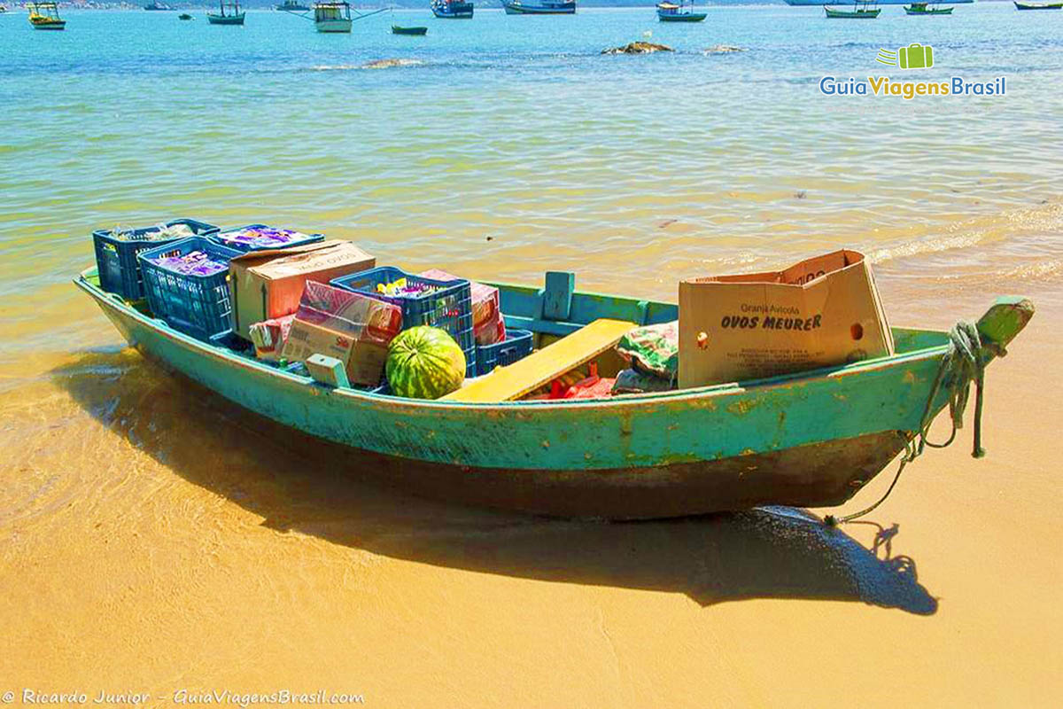 Imagem de barco com mantimentos na areia da praia.