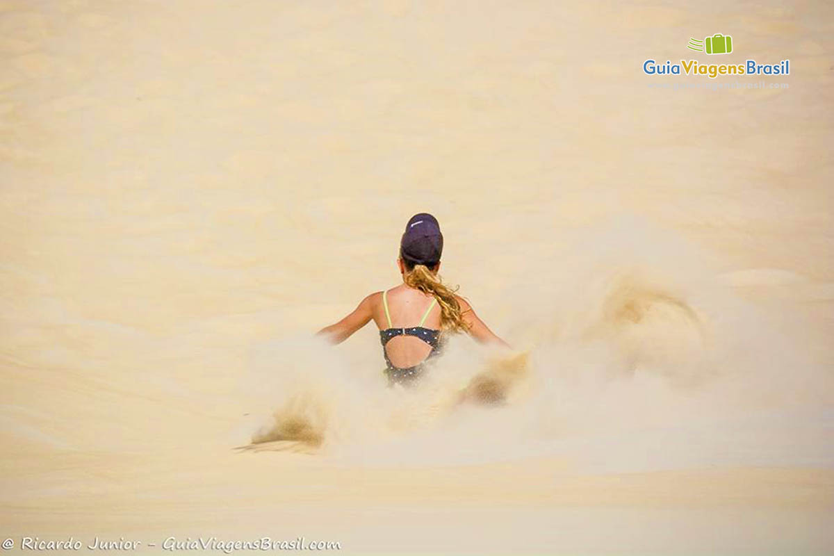 Imagem de uma pessoa descendo as Dunas e ao lado levantando areias claras das dunas.