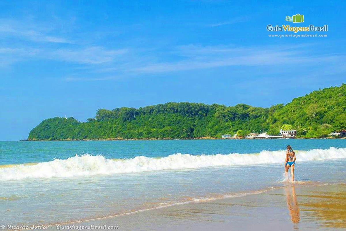 Imagem de menina andando na beira da Praia Cabeçudas.