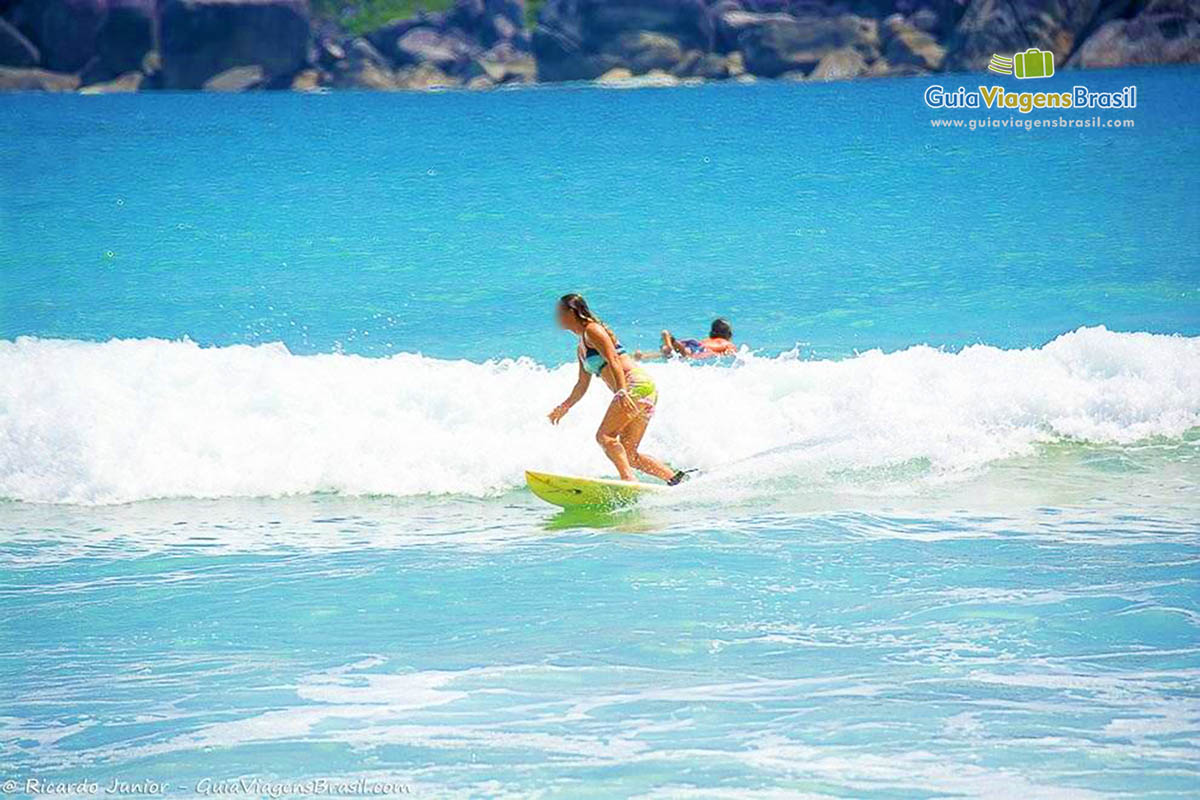 Imagem de surfista feminina no pico da onda.