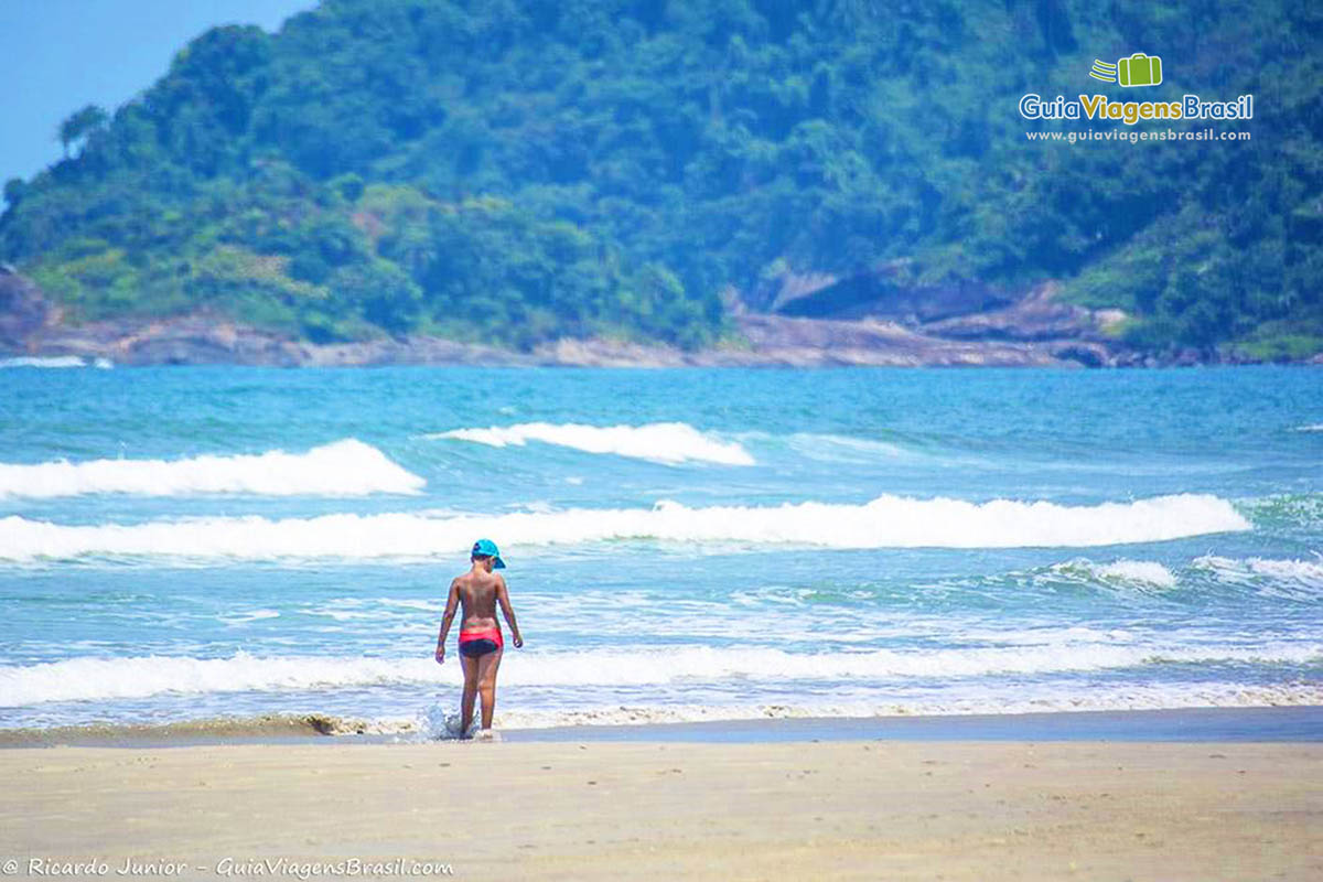 Imagem de menino brincando, correndo na beira da Praia Riviera de São Lourenço.