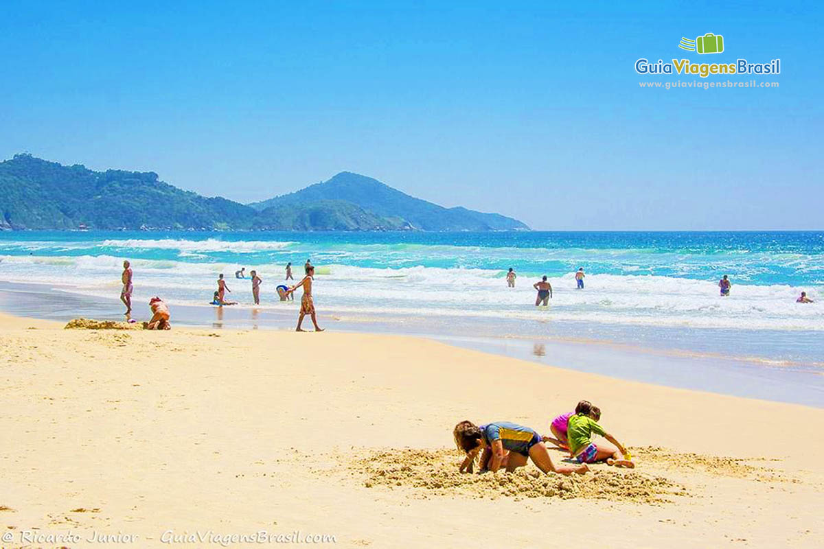 Imagem de dois meninos brincando de cavar na areia.