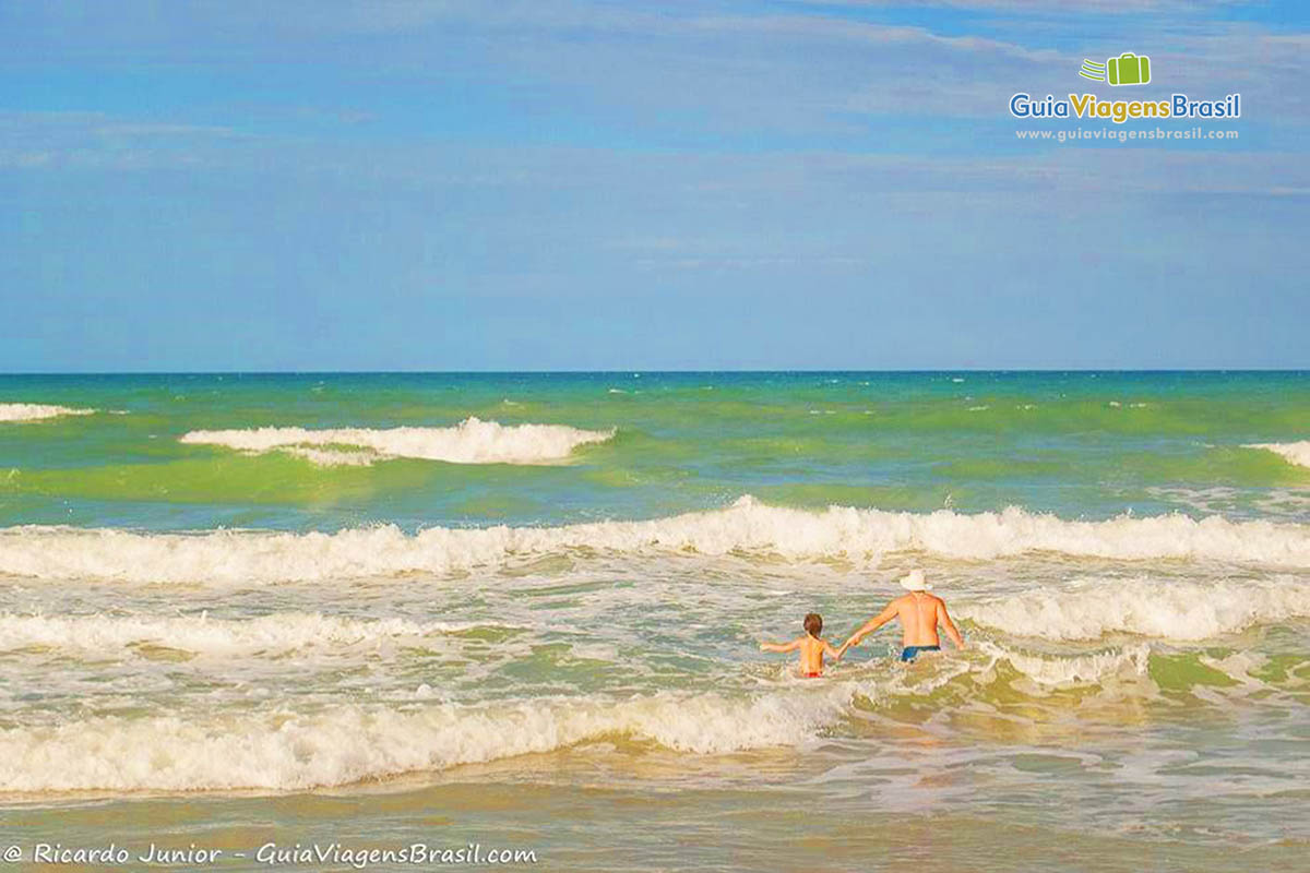 Imagem de pai e filho entrando no mar da Praia do Futuro.